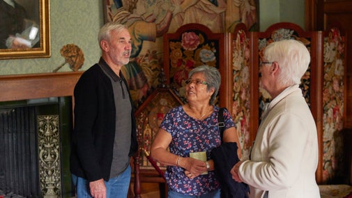 A man and two women standing in an antique furnished room at Coughton Court, Warwickshire